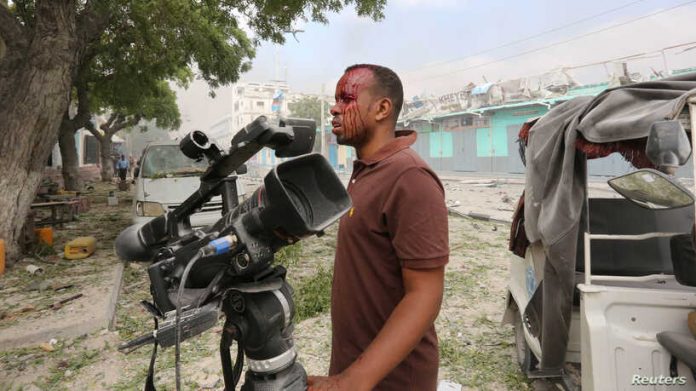 Somali Freelance journalist Mohamed Guray holds on to his camera after he was injured in a secondary explosion in front of Dayah hotel in Somalia's capital Mogadishu